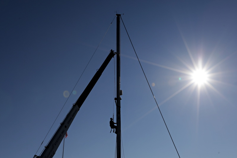 Alan Johnson of Brownell Systems finds himself high above Mattapoisett harbor as he places the strap to remove the mast of a sailboa they are pulling out of the water, as boating season comes to a close.  PHOTO PETER PEREIRA