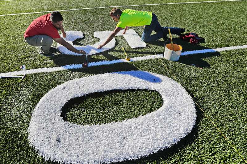 Stacey Wills and Jesus Adame of Sprinturf, align the white turf numbers, before cutting them and gluing them into place on the new football field they are constructing at Fairhaven High School in preparation for the first game to be played on the new surface sometime early next month.