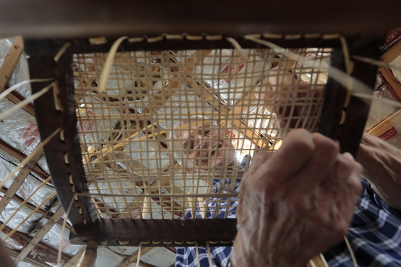 Peter Borsari works on caning a chair in his workshop at his home in Marion, MA.