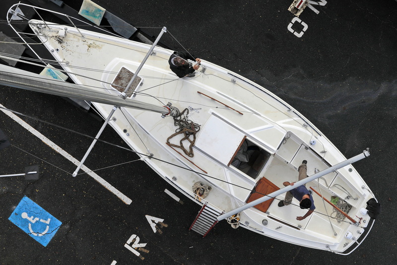 Silas Costa and Jason Costa of Triad Boatworks, remove the rigging from the mast of a sail boat they are pulling out of the water in Mattapoisett, MA as the mad rush to pull boats out of the water is well underway. PHOTO PETER PEREIRA