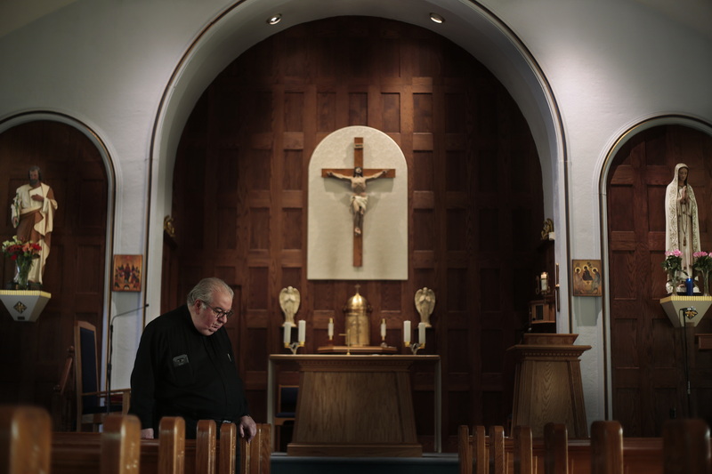 Father John Raposo stops at the pews in front of the alter in Our Lady of Fatima Church on Acushnet Avenue in New Bedford, MA one of three churches closing this weekend. PHOTO PETER PEREIRA