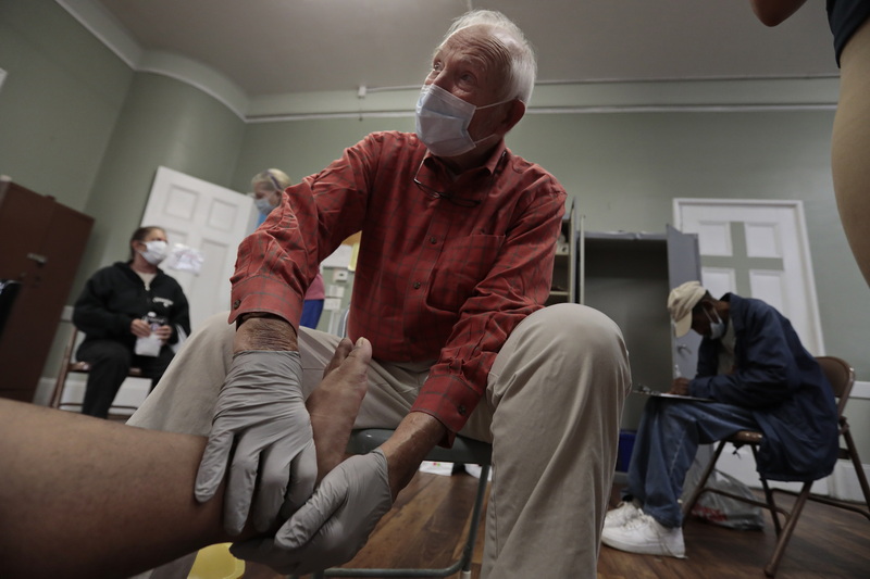 Doctor Douglas Fogg takes a closer look at the feet of a homeless man during the weekly Mercy Meals podiatry clinic for the homeless on Purchase Street in New Bedford, MA. PHOTO PETER PEREIRA