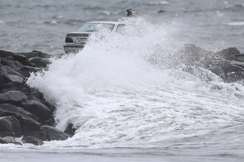 A car making its way across the Gooseberry Island causeway in Westport, MA is covered by a large wave, as a nor'easter makes its way across the Northeast.  PHOTO PETER PEREIRA