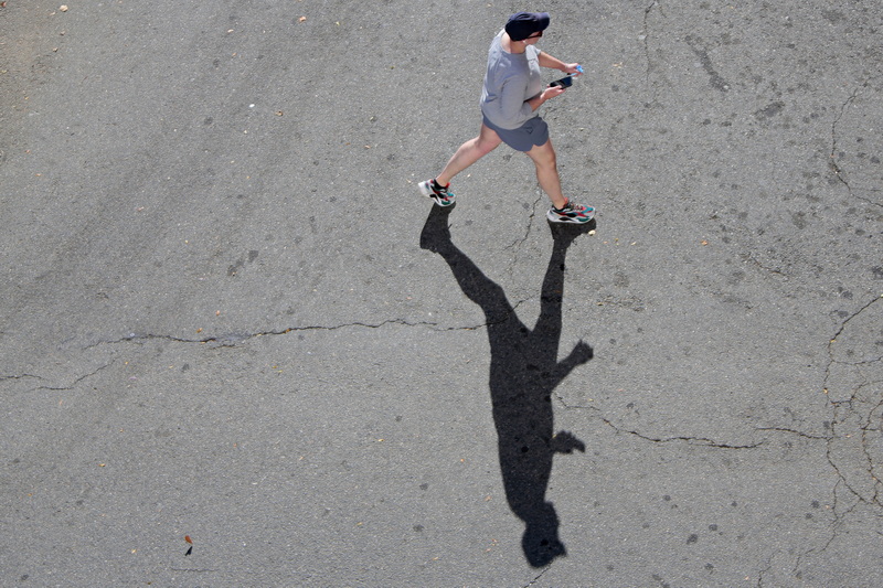 A man has his shadow for company as he walks across N Second Street in downtown New Bedford, MA as seen from the top level of the parking garage.  PHOTO PETER PEREIRA