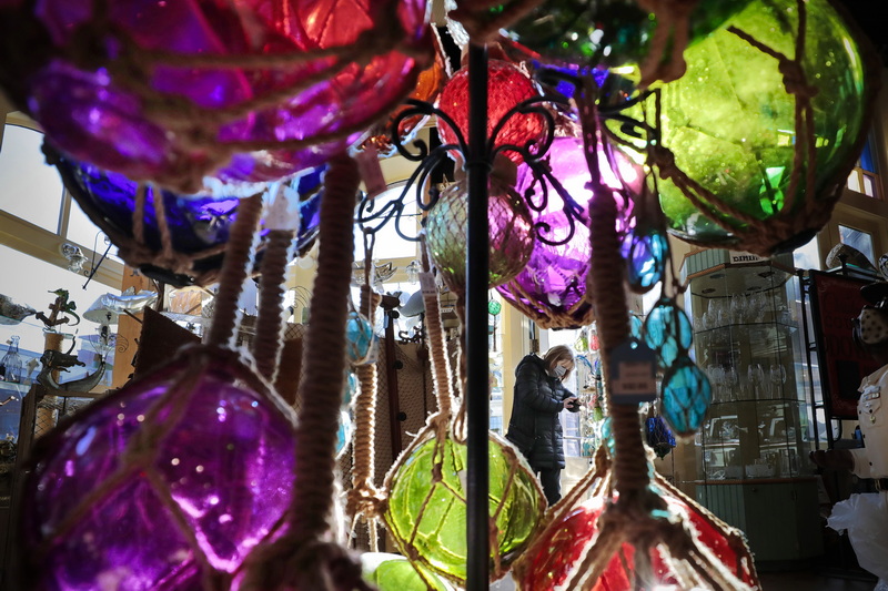 A shopper takes a closer look at some items for sale at Moby Dick Nauticals on William Street in New Bedford, MA as seen through colorful fishermen buoys for sale.  PHOTO PETER PEREIRA