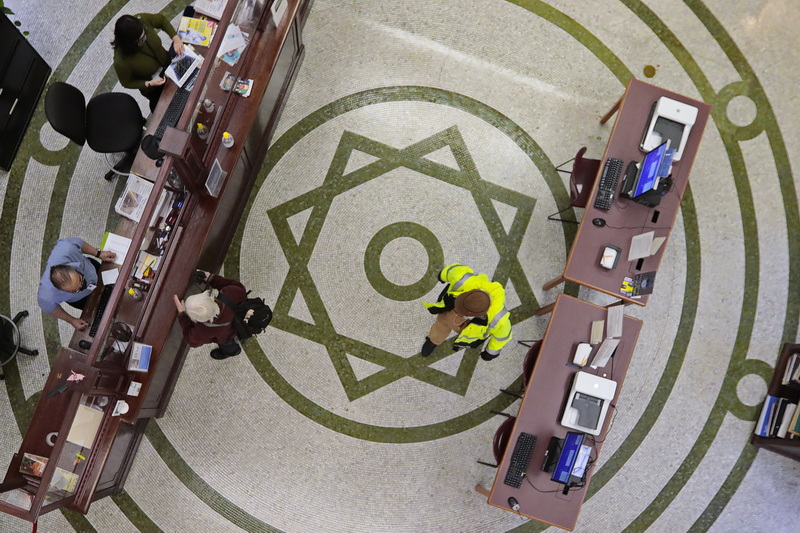 A man makes his way across the ornate tiled floor of the New Bedford, MA downtown public library, as a woman is helped by the librarians at the counter of the historic building. PHOTO PETER PEREIRA