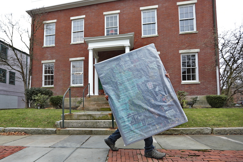 A man makes his way up William Street in downtown New Bedford, MA holding a wrapped art piece. PHOTO PETER PEREIRA