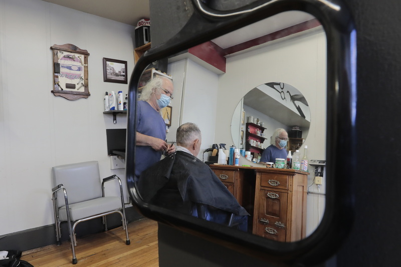 Manny Medeiros is reflected in two mirrors as he gives a patron a haircut at Your Father's Mustache on Purchase Street in downtown New Bedford, MA. PHOTO PETER PEREIRA