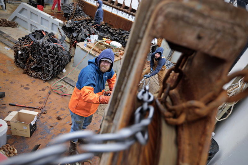 New Bedford, MA: Mike Asci, left, and fellow crewmembers of the scalloper Patriots, pull in two hundred feet of new chain they will install on the dredges, using one of the ships large pulleys.