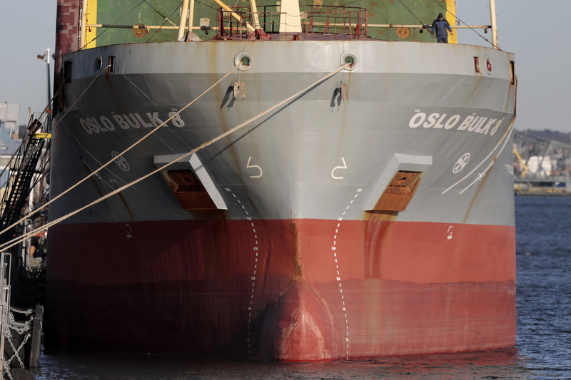 A man is dwarfed by the Oslo Bulk 8 cargo ship unloading utility poles at the South Terminal in New Bedford, MA.