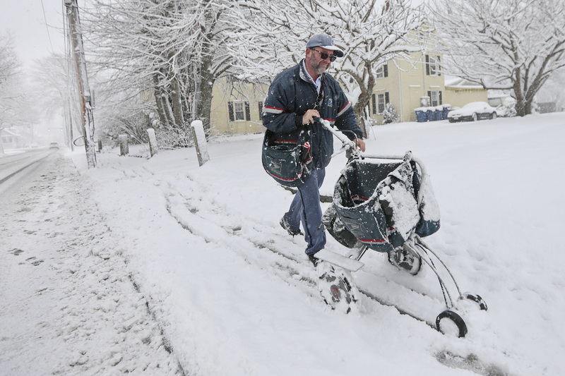 Postman Josh Ashley fights the driving snow and cold weather, as he make his way up Main Street in Fairhaven using a cart to deliver mail during the first snowstorm of the year.