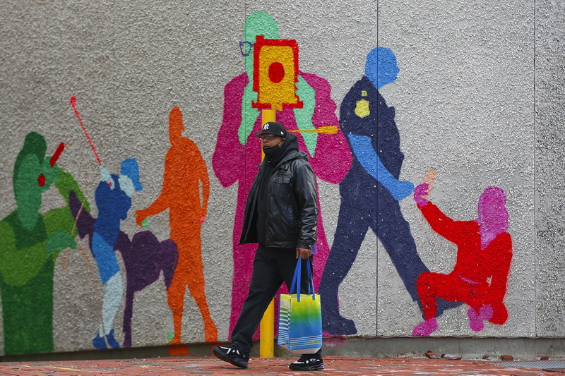 A man has his photo taken by a colorful character painted on the walls of the Sears Court in downtown New Bedford, MA as he make his way up Pleasant Street.