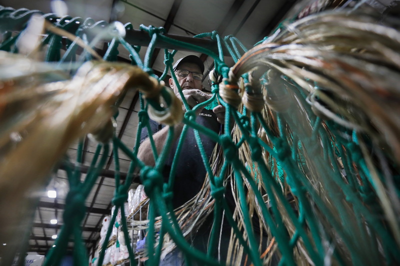 Ernesto Pimental, net technician, installs the nylon protection on the chaffing gear net he is making at Luzo Fishing Gear in New Bedford, MA.  This thirty foot net he is making will be sewn to the bottom of a regular fishing net and will protect it from being torn when it is towed along the seafloor.