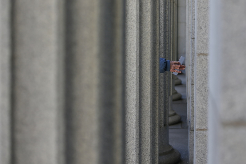 A man holding a letter reaches for the door to the entrance of the downtown New Bedford, MA post office, as seen through the colonnade of Corinthian columns which line the facade of the historic building.  PHOTO PETER PEREIRA