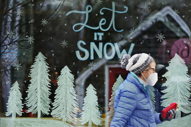 A woman walks past the Farm & Coast Market window in Dartmouth, MA forcasting the snow storm that is scheduled to hit the region tomorrow. PHOTO PETER PEREIRA