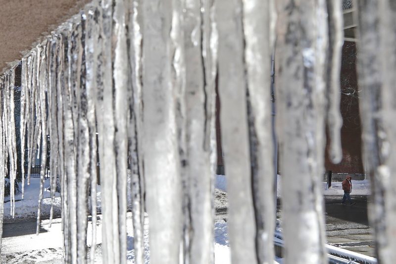 A man is framed by the icicles hanging from the side of the Bay Coast Bank building, as he makes his way across Elm Street in downtown New Bedford, MA.