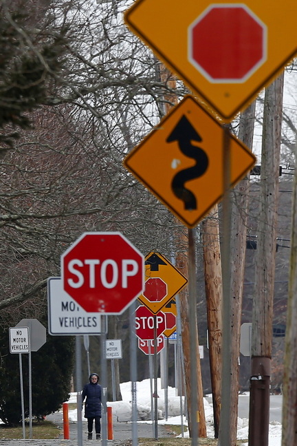 A pedestrian is surrounded by signs as she makes her way up the walk/bike path adjacent to South Street in Fairhaven, MA.  PHOTO PETER PEREIRA