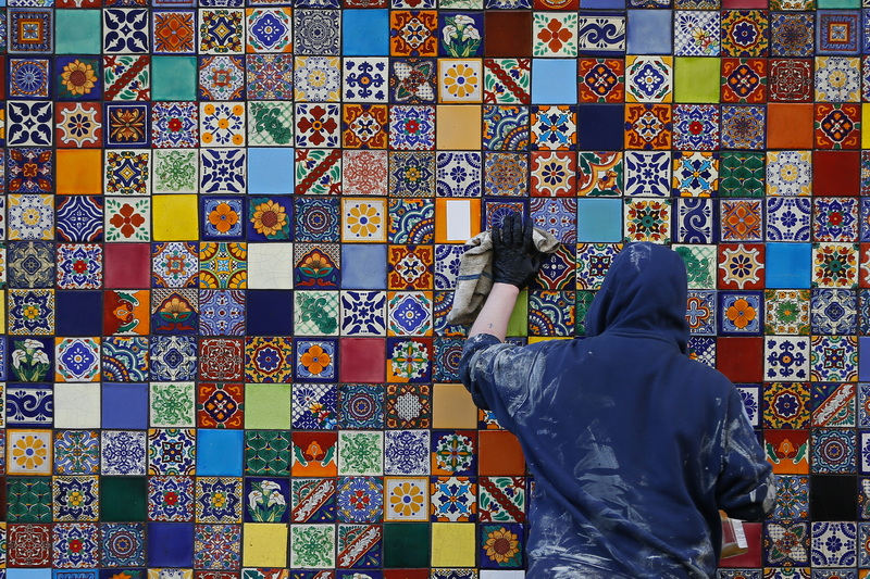 Casey Wiencek is surrounded by color as he cleans the tile on the side of No Problemo in downtown New Bedford, MA. PHOTO PETER PEREIRA