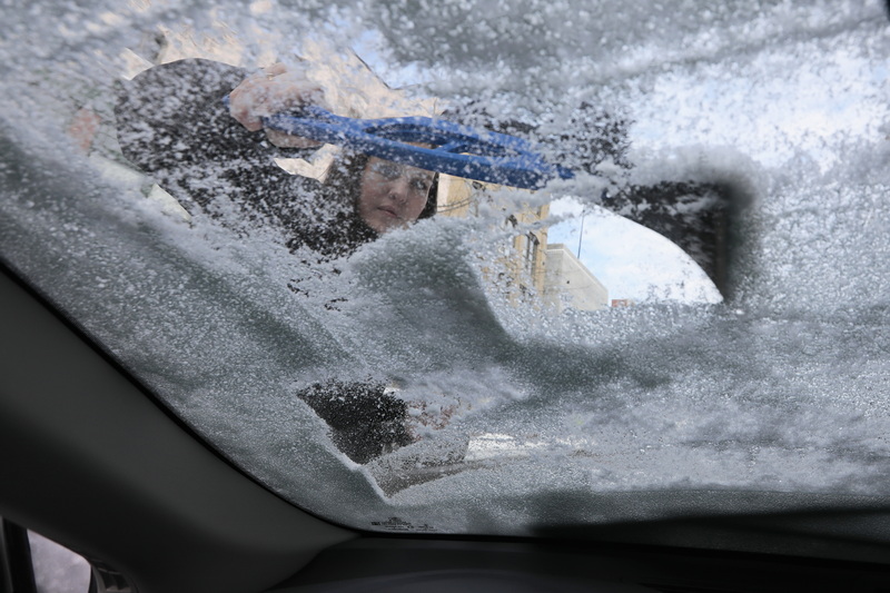 Heather Romano scrapes the ice from the windshield of her vehicle in New Bedford, MA after another round of snowfall which covered the region. PHOTO PETER PEREIRA