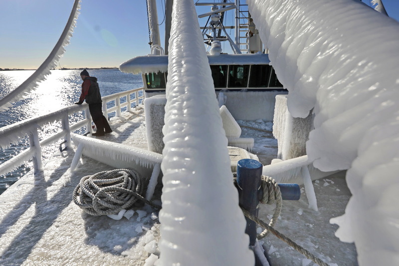 Chad Schneider, mate of the F/V Nancy Elizabeth, walks across the frozen bow of the fishing boat, which returned to New Bedford, MA in part due to the extreme weather and ice build up.  PHOTO PETER PEREIRA