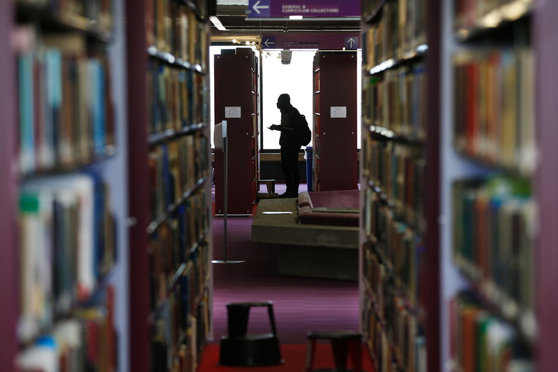 A student looks for a book on the shelves of the fifth floor UMass Dartmouth University library in Dartmouth, MA. PHOTO PETER PEREIRA