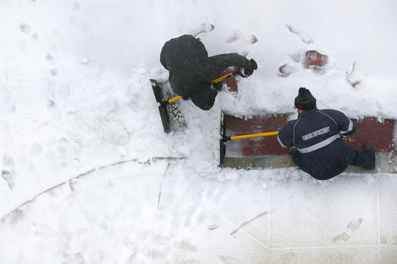 Parking attendants clear the crosswalk in front of the public garage in downtown New Bedford, MA after another snow storm covered the area. PHOTO PETER PEREIRA