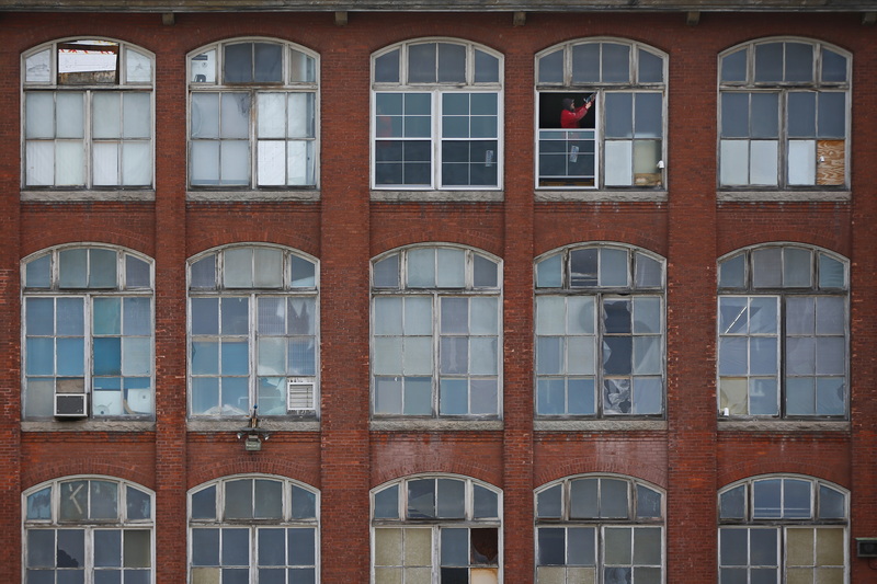 A carpenter install new windows on the top level of the Hatch Street studios in the north end of New Bedford, MA. PHOTO PETER PEREIRA