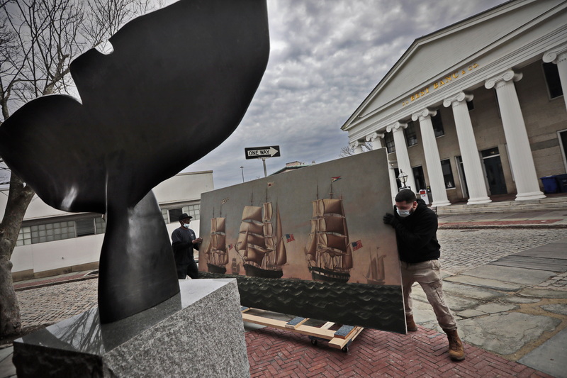 Joe Christmas, left, and Jose Adorno of J.J. Web Moving & Storage, wheel a painting by Charles Sidney Raleigh, of three whaleships from New Bedford, past the whale tale sculpture in front of the Whaling Museum on N Water Street in New Bedford, as they take it from the Waddle Gallery to conservation storage in another part of the museum.  This painting along with a series of other paintings of whale ships date to the late 1800's and were part of a panorama which told the journey of the whale ship Niger (ship on right of painting) before it was cut into pieces in 1958. PHOTO PETER PEREIRA