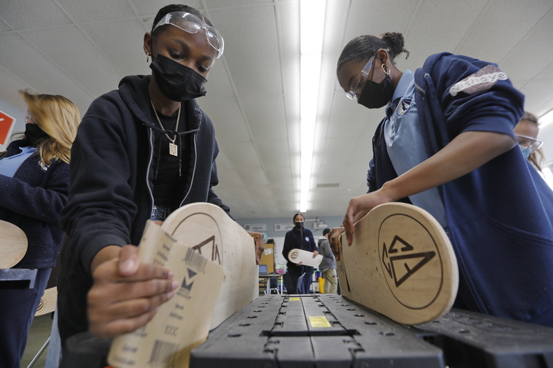 Our Sisters' School students Priseis Gray, 14, and her twin sister Nishaye Gray, 14, work on sanding the skateboards they are making under the guidance of the Community Boating Center in New Bedford, MA.  PHOTO PETER PEREIRA