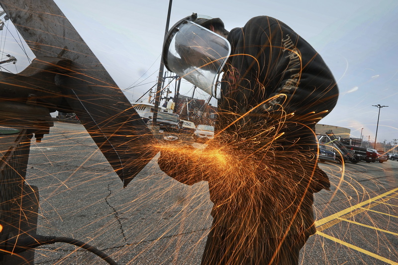 Chris Macedo of Macedo Welding sends sparks flying as he cuts some steel which he is custom fabricating for windows for a fishing boat being repaired in New Bedford,  MA. PHOTO PETER PEREIRA