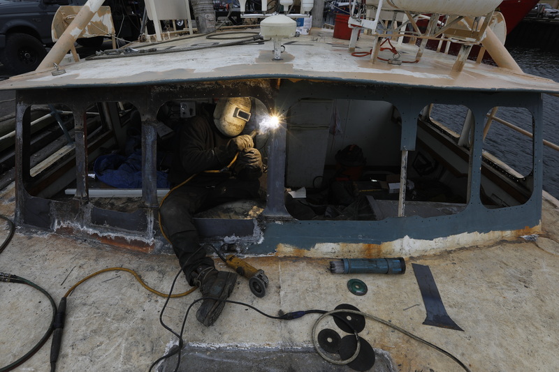 Chris Macedo of Macedo Welding makes repairs to the windows of the fishing boat Independence docked in New Bedford, MA.  PHOTO PETER PEREIRA