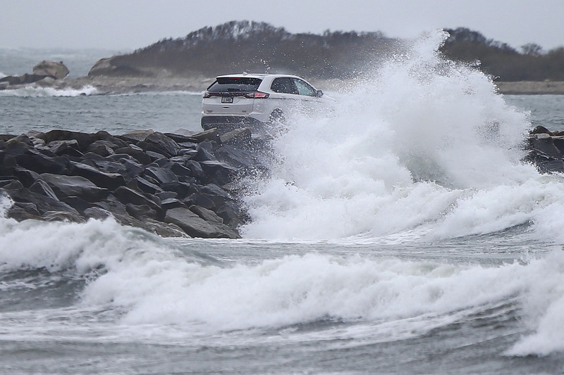 A vehicle makes its way across as high winds amplify the waves, as they crash onto the Gooseberry Island causeway in Westport, MA  PHOTO PETER PEREIRA