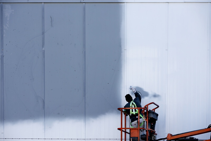 A painter sprays a fresh coat of paint on the side of the Foley Fish Co. building in New Bedford, MA.  PHOTO PETER PEREIRA