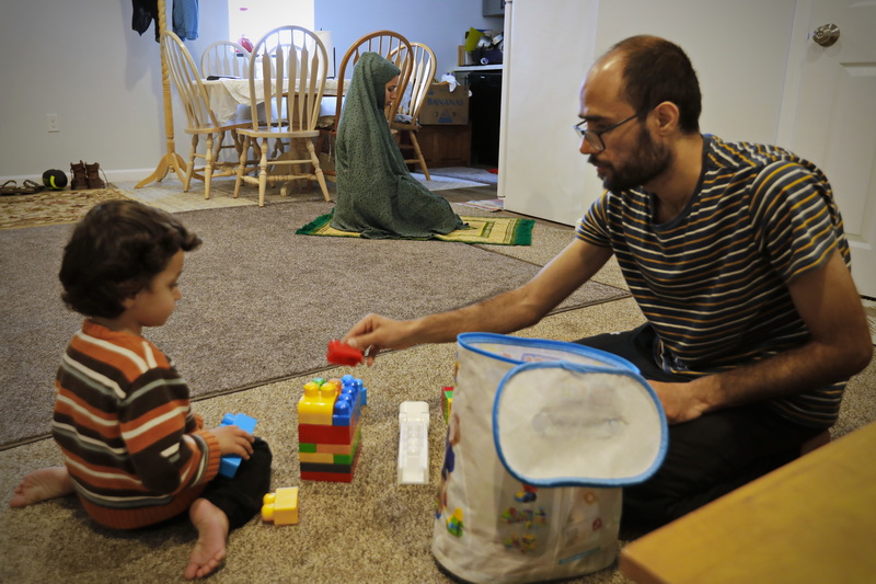 Khalida Hakimi is seen praying in the background, as Khalid Omar plays with his son Ferdous Omar, 2, before praying himself once his wife is done, during their first Ramadan outside of their native Afghanistan.  Khalid, Khalida and their son Ferdous have been living in New Bedford, MA since November of last year when they left their home in Kabul, Afghanistan. PHOTO PETER PEREIRA