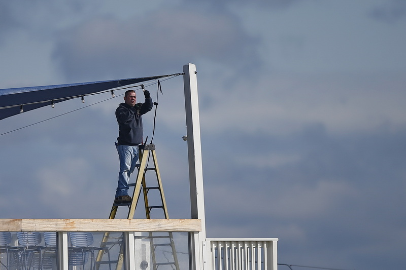 A worker installs lights on the upper deck of the Cisco Kitchen & Bar restaurant in New Bedford, MA. PHOTO PETER PEREIRA