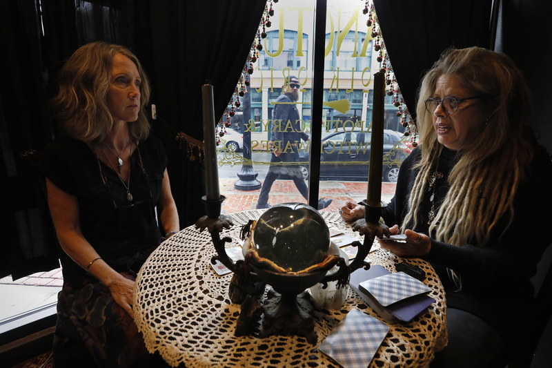 A man walking up Purchase Street looks in as Jodi 'Lucky' Ventura, right, gives Dory Dixon a psychic reading in the new room of Sanctum Folklorica in downtown New Bedford.