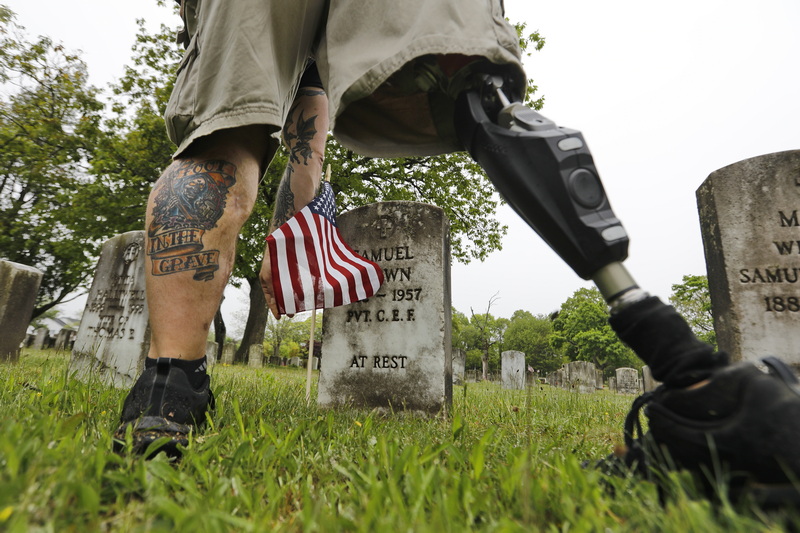 Christopher Gomes, veteran agent for the city of New Bedford, places American flags at the graves of veterans buried at the Pine Grove Cemetery in preparation for Memorial Day.  Mr. Gomes, an Army veteran, lost his right leg when an IED exploded while serving in Iraq in 2008.  PHOTO PETER PEREIRA