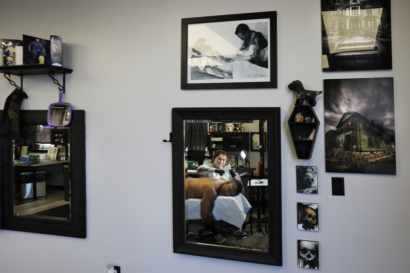 Rachel Garnette is reflected in the mirror hanging on the wall of the New Bedord Tattoo Co. as she gives Donald Tavares a new tattoo on his shoulder. PHOTO PETER PEREIRA