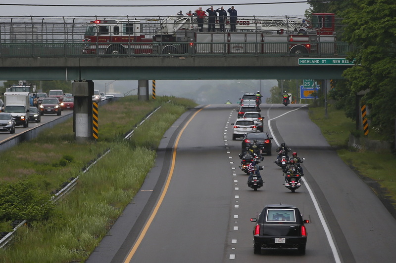 New Bedford firefighters stand at attention as the hearse carrying Sergeant First Class William James 