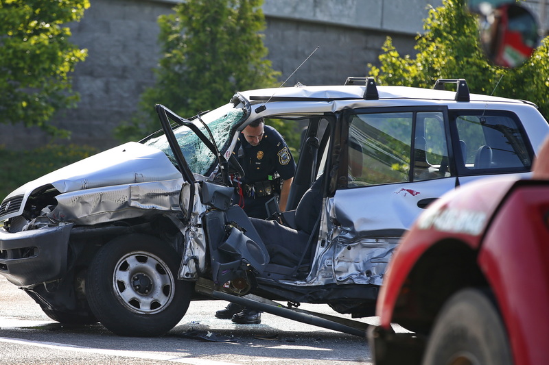 A New Bedford police officer looks into the SUV which was struck by the red truck in the foreground at the intersection of Route 18 and Elm Street in New Bedford, MA.  PHOTO PETER PEREIRA