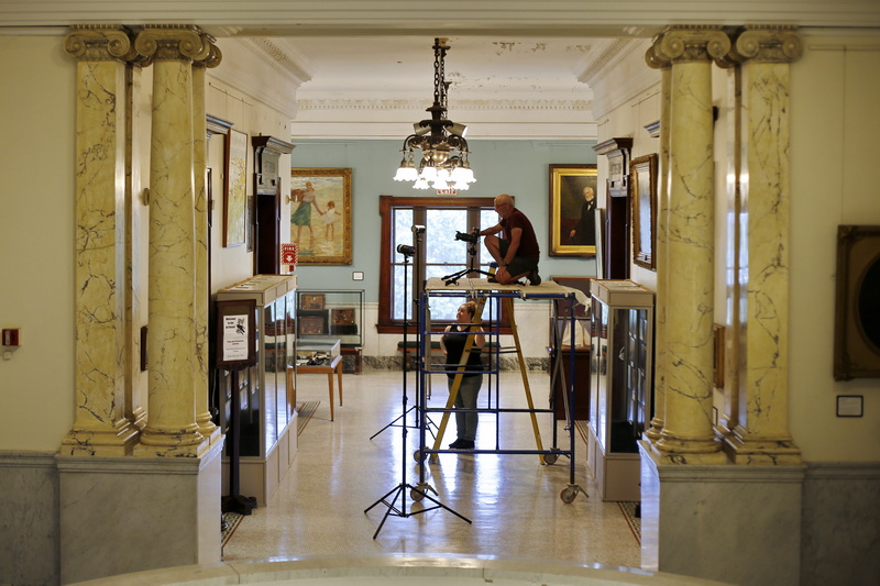 Phillip Mello photographs the New Bedford downtown libraries vast art collection as part of an incentive by art director, Alexandra Copeland, bottom, to make the work more accessible. PHOTO PETER PEREIRA