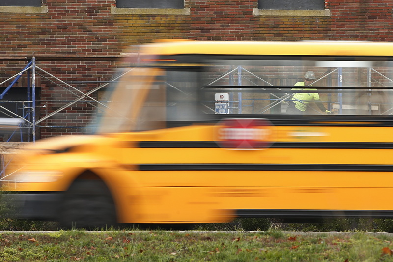 A worker installing staging on the side of the former National Club at the bottom of Union Street in New Bedford, MA is seen through the windows of a school bus driving on Route 18.  PHOTO PETER PEREIRA