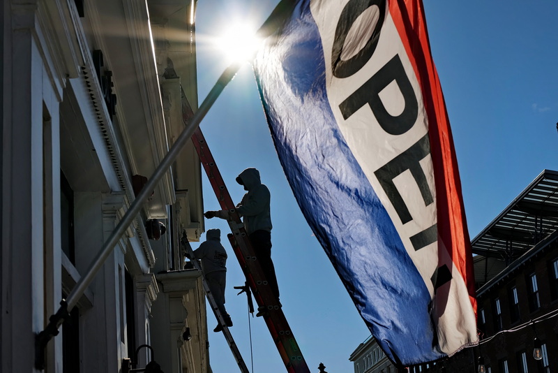 Top Level in Painting painters step up to the task on the building adjacent to the Tia Maria's European Cafe whose open flag is seen in the foreground on N Water Street in New Bedford.