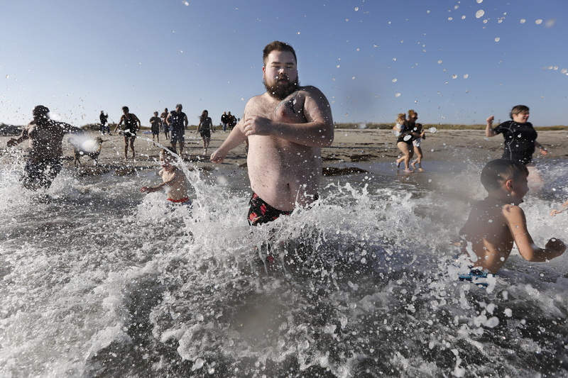 Tyler O'Driscoll leads the charge as he and fellow participants jump into the cold waters off Gooseberry Island in Westport, MA during the annual Plunge of the Faithful.  The event is held in memory of Shannon O'Driscoll who was killed in 2006 by an SUV driver while holding a sign supporting organized day care programs in the state. This is part of a fundraiser, which has raised over 20K dollars since it began. PHOTO PETER PEREIRA