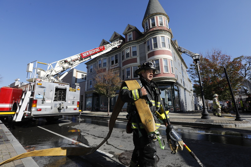 New Bedford firefighter Mark Pacheco carries the hose after  responding to a fire at 1168 Acushnet Avenue in New Bedford, MA. PHOTO PETER PEREIRA