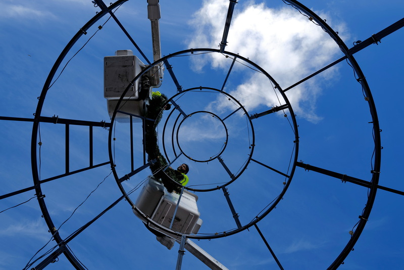 Jonathan Carol and Carlos Medina of New Bedford DPI find themselves high in the air as they install the top section of the giant Christmas Tree they are building at the intersection of Route 18 and Union Street, as seen from below. PHOTO PETER PEREIRA