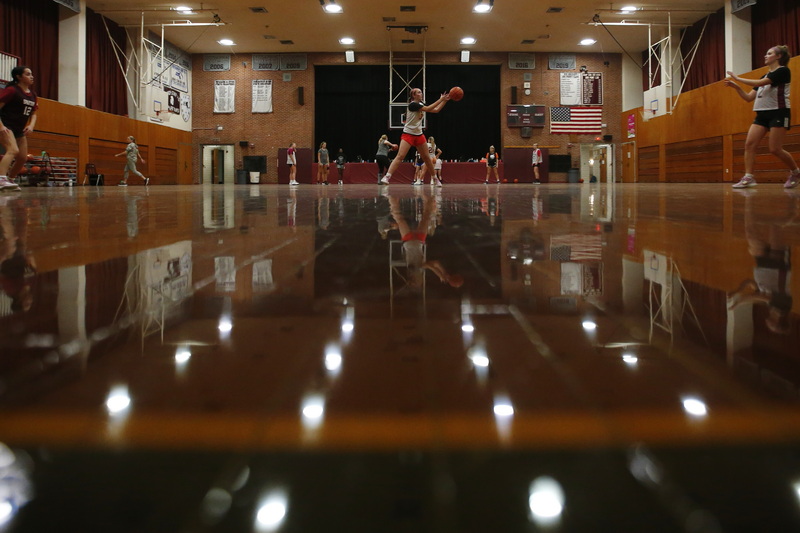 Sophine Caldwell, center, takes a pass as she and fellow Bishop Stang High School girls basketball team members are reflected from the shiny floors of the school's gym as they prepare for the upcoming season.  PHOTO PETER PEREIRA