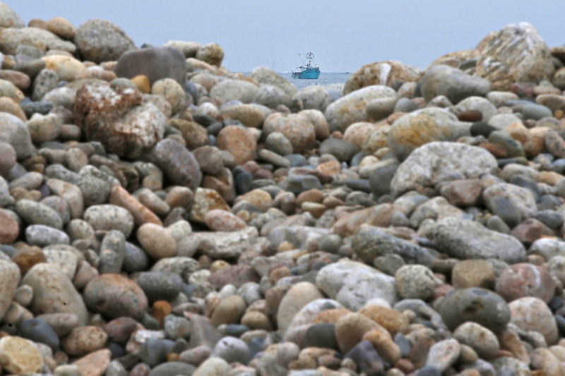 A lobster boat is seen between a trough in the stones piled up on the edge of East Beach Road in Westport, MA. PHOTO PETER PEREIRA