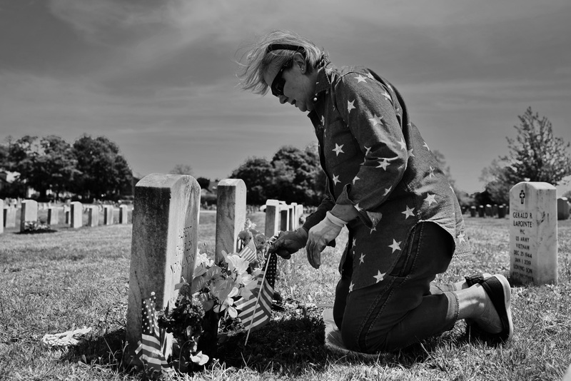 Diane Leclair places flowers and American flags in front of her father Albert Charles Normandin's grave at Pine Grove Cemetery in New Bedford, MA in preparation for Memorial Day.  Mr. Normandin was a Marine during WWII and fought during the battle of Iwo Jima.