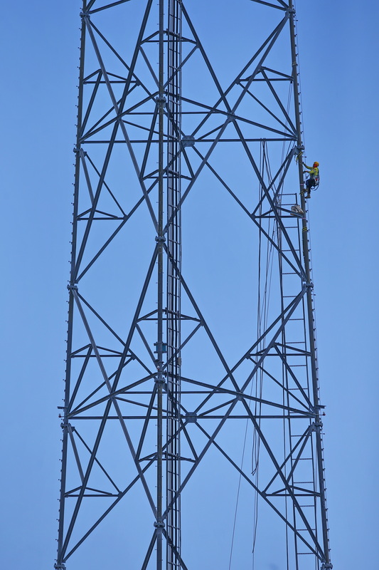 A technician scales the giant antenna near South Front Street in New Bedford, MA to install new wiring. PHOTO PETER PEREIRA